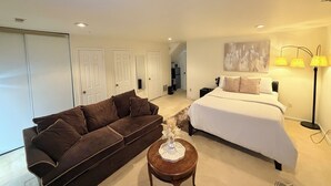 A bedroom with a bed, a brown sofa, a small table with a vase, and a lamp. - Cozy 1-bedroom studio in tranquil Laurel with AC (Laurel)