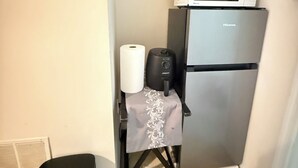 A compact kitchenette with a silver refrigerator, a microwave, a small air purifier, and a trash bin. - Cozy 1-bedroom studio in tranquil Laurel with AC (Laurel)