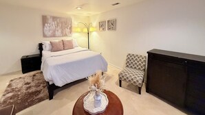 A bedroom with a bed, bedside tables, a lamp, a chair, and a TV stand. - Cozy 1-bedroom studio in tranquil Laurel with AC (Laurel)