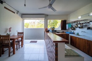 Une cuisine moderne avec un coin repas, un ventilateur de plafond et une vue sur la verdure environnante.
