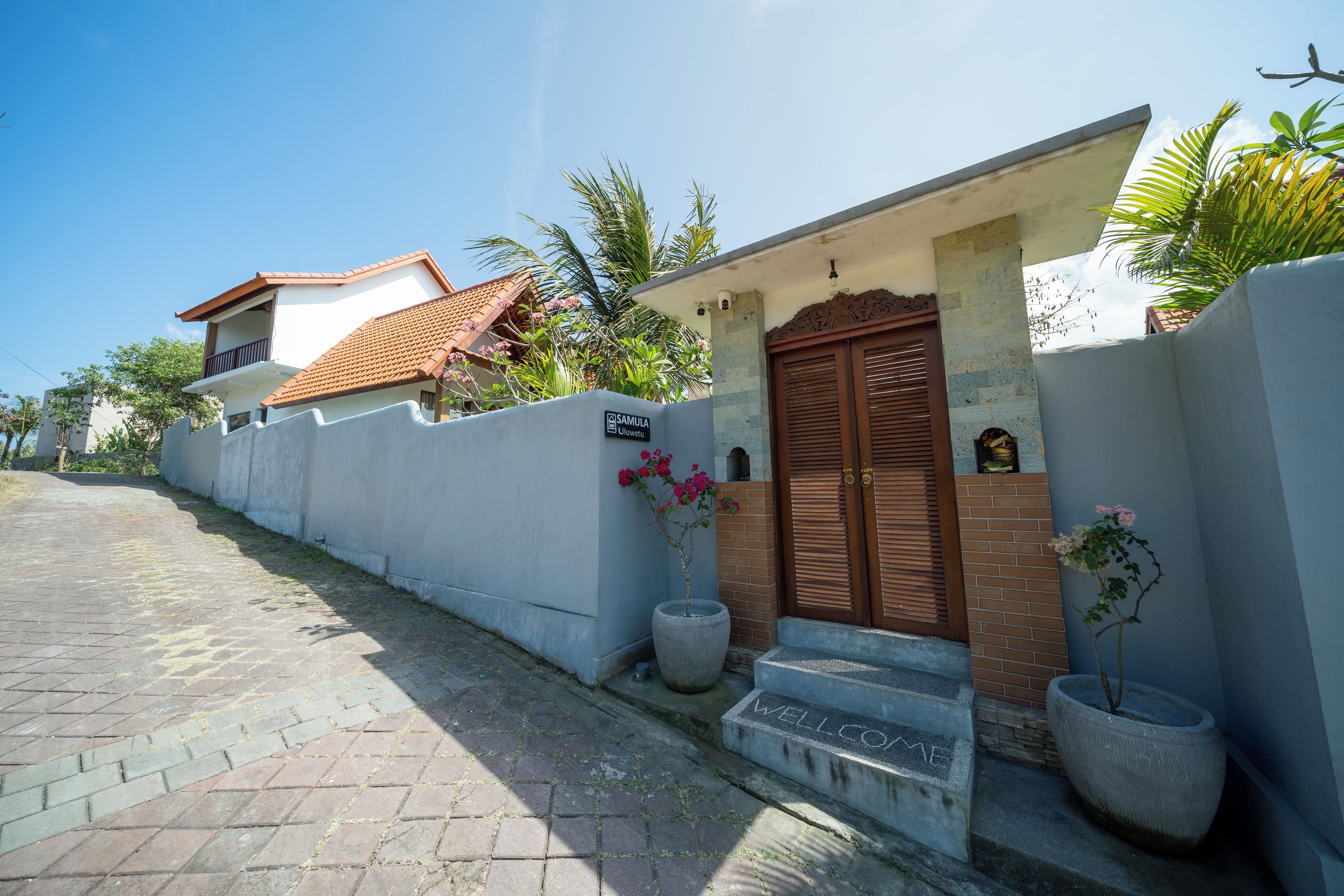 Una propiedad residencial con entrada porticada, un jardín cuidado y un camino de acceso pavimentado.