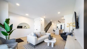 Una sala moderna con un sofá, una mesa de centro y una escalera que lleva a una cocina.