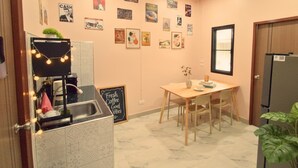 A cozy room with a kitchen area, a dining table, and a refrigerator. - 3-Min Walk to Beach • Super Private 2 BR House (Tambon Patong)
