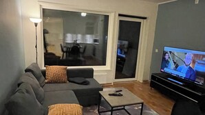 En moderne stue med en grå sofa, et sofabord og et fjernsyn.