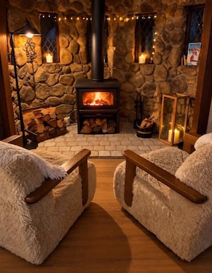 A cozy room with a stone fireplace, two plush armchairs, and a wooden floor. - The Botanical Castle, beside the Botanic Gardens, Mt Tamborine (Tamborine Mountain)