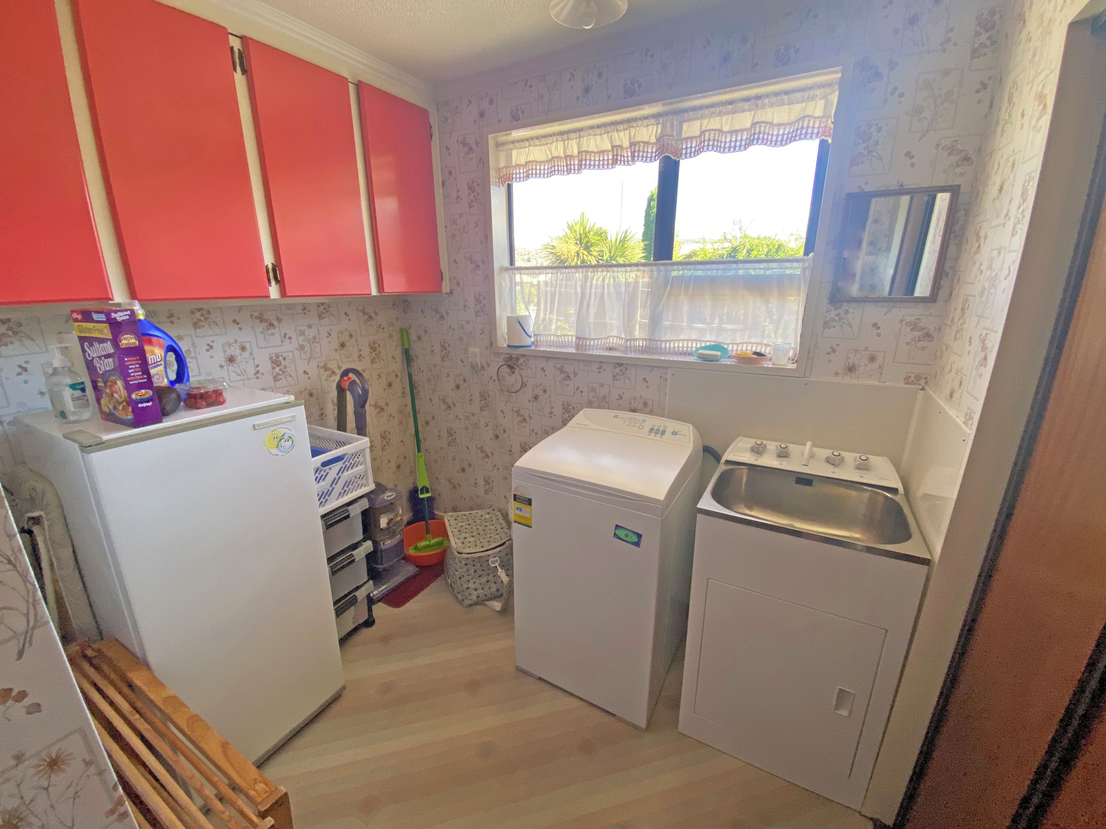 A compact kitchen with a refrigerator, washing machine, and sink.