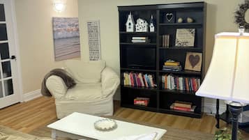 Un salon avec un canapé beige, une table basse blanche, une bibliothèque et une lampe.