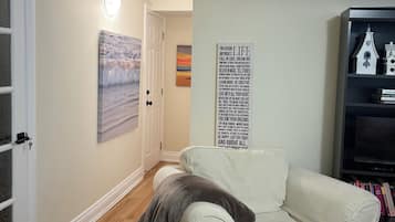 A living room with a beige couch, a wall with a motivational quote, and a bookshelf with books and a model house.