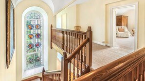 Eine Treppe mit Holzwertungen führt zu einem Raum mit einem großen Buntglasfenster.