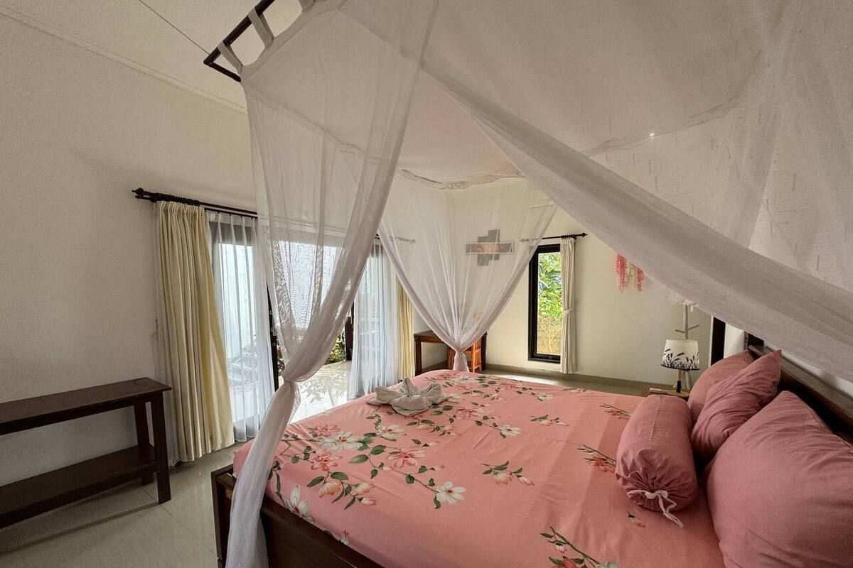 Una camera da letto con un letto a baldacchino, un comodino e una panca.