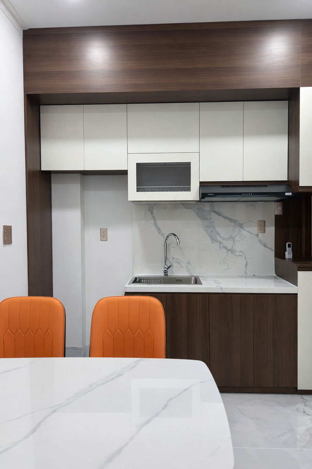 A compact kitchen with white cabinets, a built-in microwave, and a stainless steel sink.