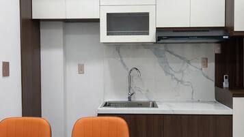 A compact kitchen with white cabinets, a built-in microwave, and a stainless steel sink.