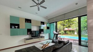 A modern living room with a sofa, TV, and a treadmill.