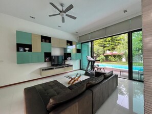 A modern living room with a sofa, TV, and a treadmill. - AP House (Bangkok)