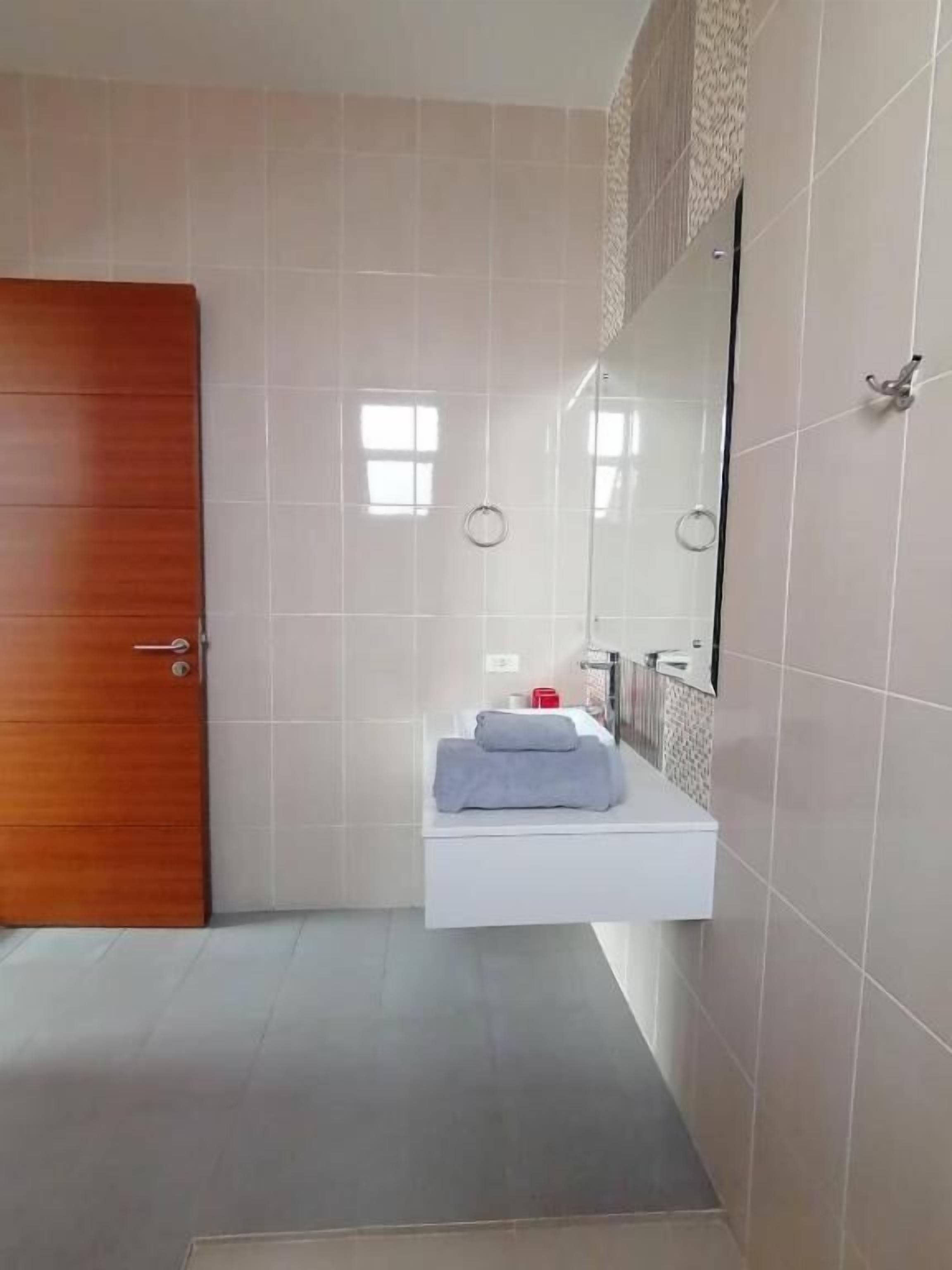A bathroom with a wooden door, a white sink with a towel, and a mirror.