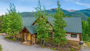 Eine Lodge mit einer Steinfassade, einer Holzterrasse und Blick auf die Berge.