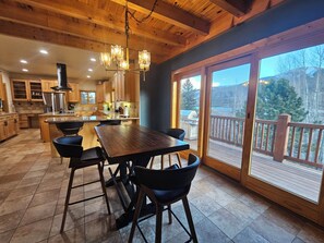 A spacious kitchen with wooden cabinets, a large island, and a view of a deck and mountains. - Luxurious retreat with grand views of Twin Lakes and the Sawatch Mountain Range (Twin Lakes)