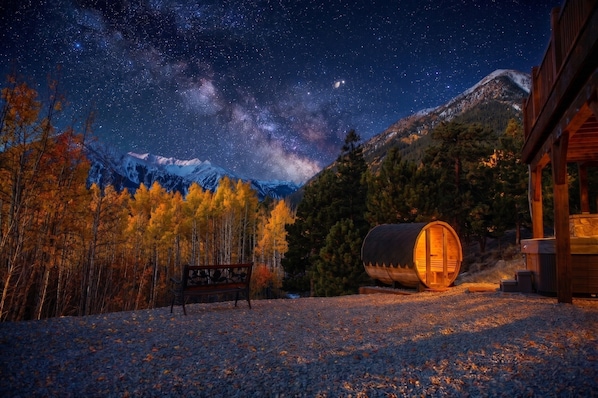 A cabin with a starry night sky, a wooden bench, and a log cabin structure. - Luxurious retreat with grand views of Twin Lakes and the Sawatch Mountain Range (Twin Lakes)