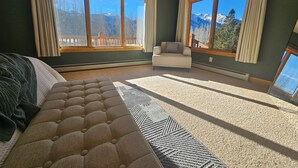 Ein Schlafzimmer mit einem großen Bett, einem Sofa und zwei fensterhohen Vorhängen.