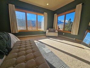 A bedroom with a large bed, a sofa, and two windows with curtains. - Luxurious retreat with grand views of Twin Lakes and the Sawatch Mountain Range (Twin Lakes)