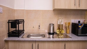 Een keuken met een roestvrijstalen spoelbak, een koffiezetapparaat en een magnetron.