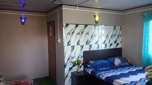 Una camera da letto con un letto, un comodino, un vaso con fiori e una parete decorata.
