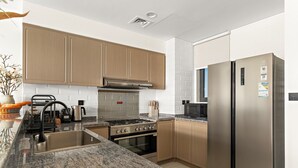 Una cocina moderna con encimeras de granito, electrodomésticos de acero inoxidable y armarios de madera.