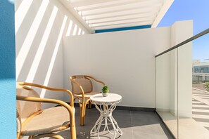 Ein Balkon mit Korbstühlen, einem kleinen runden Tisch und einem Blumentopf.