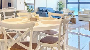 Una sala de estar moderna con comedor, ventanas amplias y vista al mar.