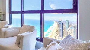 Un salón moderno con un ventanal grande que ofrece vistas a la playa y al paisaje urbano.
