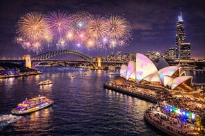 Ein Nachtblick auf das Sydney Opera House und die Harbour Bridge in Sydney, im Hintergrund ein Feuerwerk.
