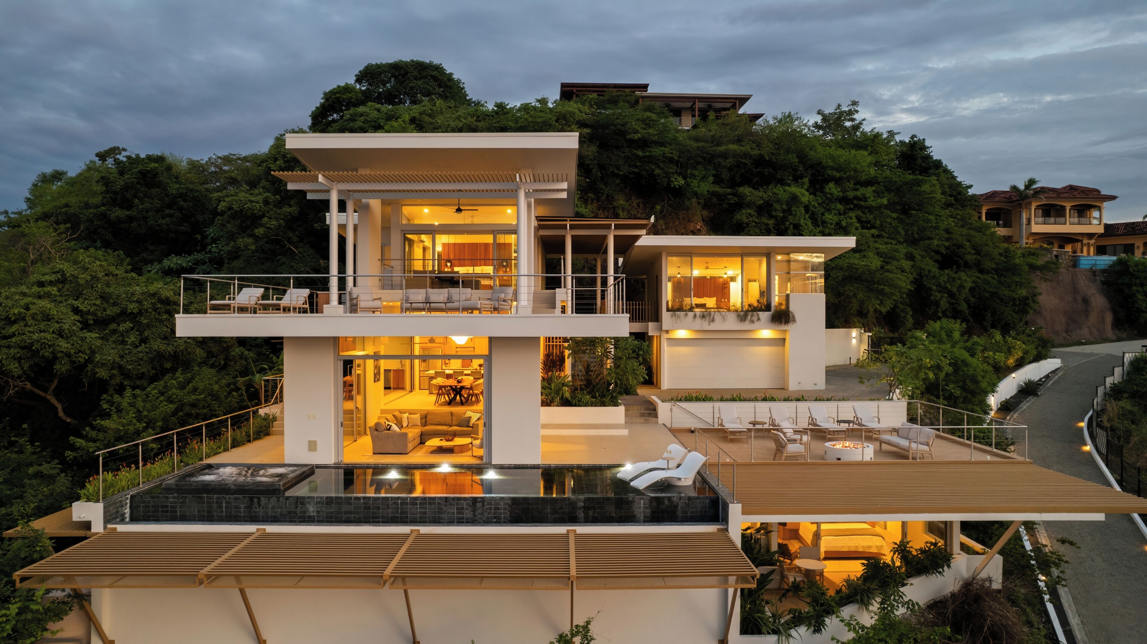 A modern multi-story house with a rooftop pool, outdoor seating, and a large balcony.