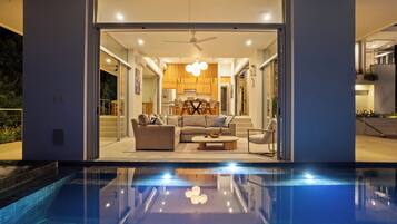 A modern interior with a pool, a sofa set, and a dining area.