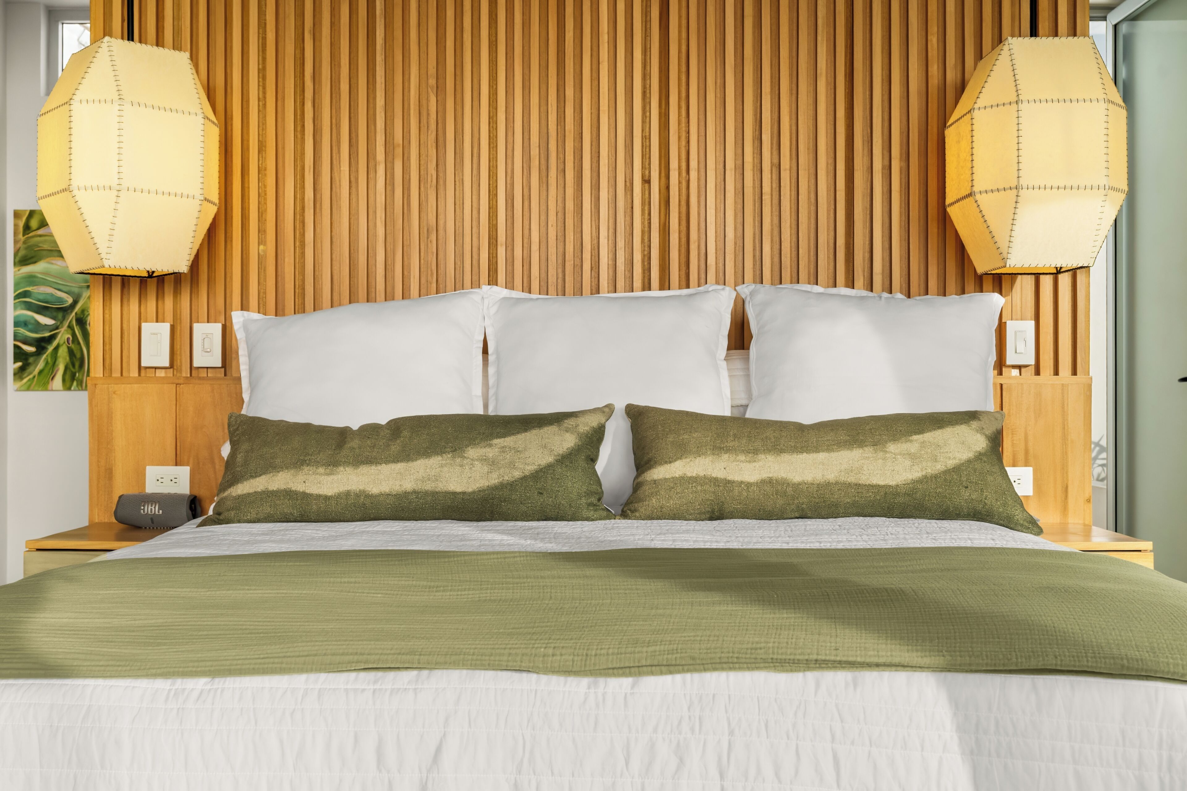 A bed with a wooden headboard, white pillows, and a green blanket.