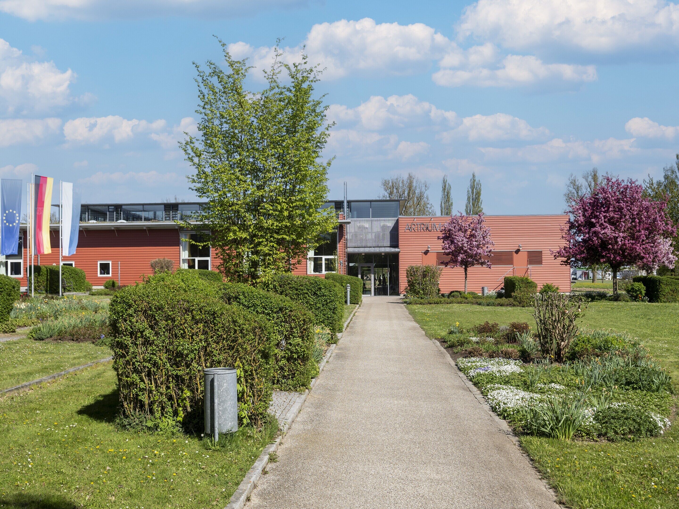 A pathway leading to a building with a red facade and a sign reading 'ARTINUM.'