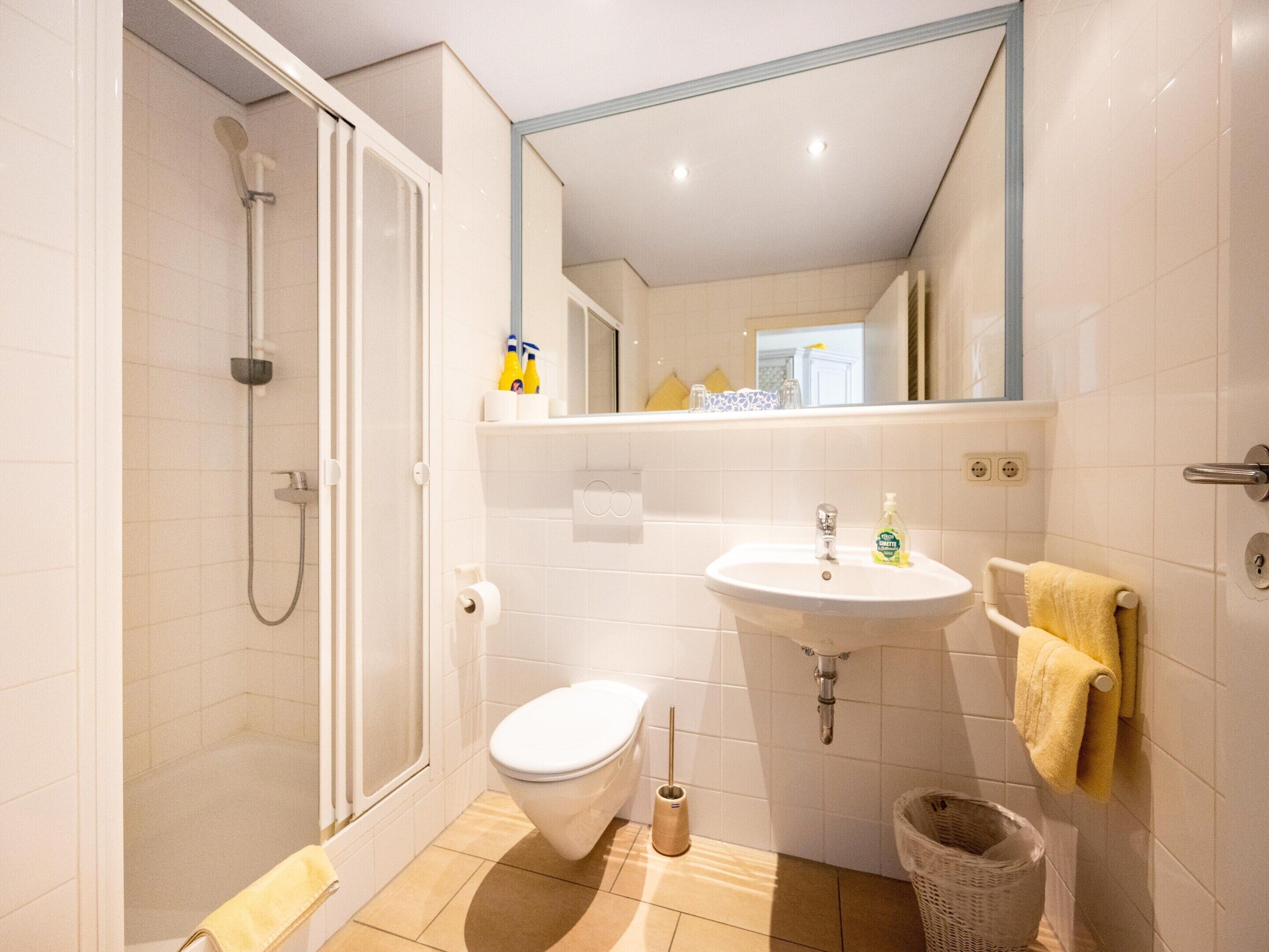 Ein Badezimmer mit Dusche, Toilette, Waschbecken und Spiegel.