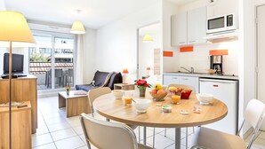 A modern hotel room with a dining area, kitchenette, and a view of the outside. - Cap Med by Interhome (Le Grau du Roi)