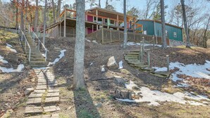 Une cabane dotée d’une terrasse en bois, d’un escalier et d’un petit porche.