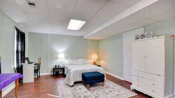 Ein Schlafzimmer mit Bett, Schreibtisch, Stuhl, Kleiderschrank und einem kleinen Tisch mit Lampe.