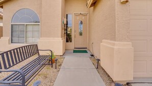 En beige byggnad med en bänk, en dörr och ett fönster.