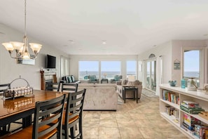 A spacious living area with a dining table, chairs, a sofa, and a bookshelf. - Trail’s End: Ocean Views, Hot Tub, Game Room & Beach Access, Pet Friendly, 2 Miles to Casino (Lincoln City)