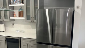 A modern kitchen with stainless steel appliances, grey cabinetry, and a white countertop.