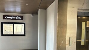 A hotel corridor with a sign for Cornerstone Suites, a marble wall, and an elevator.