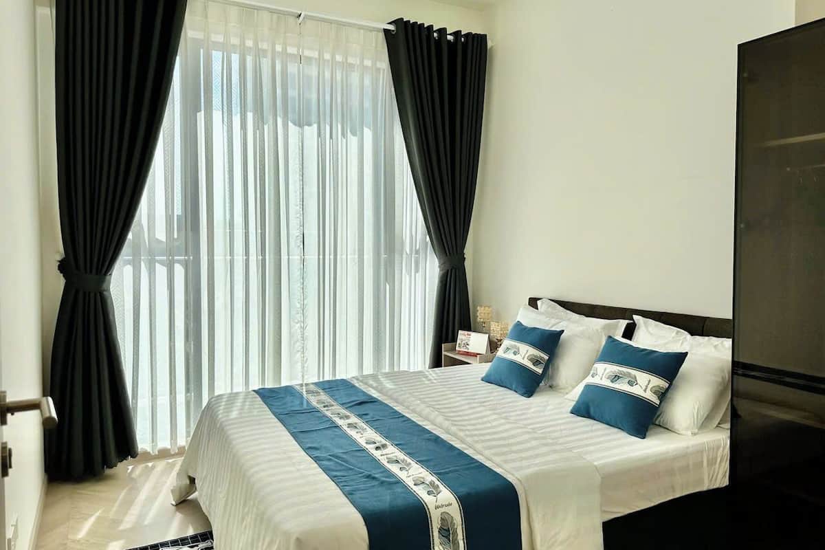 Une chambre d’hôtel avec un lit, des rideaux, une table de chevet et un téléviseur.