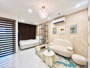 Un salon moderne comprenant un canapé, une petite table ronde, un tapis décoratif, un luminaire au plafond et un climatiseur fixé au mur.