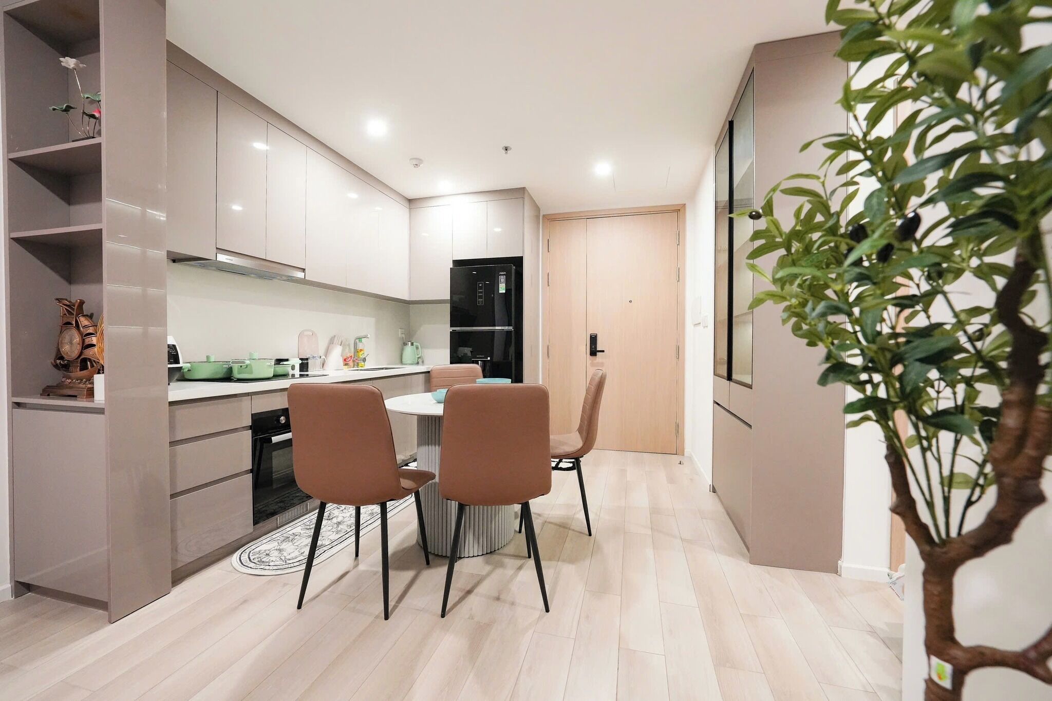 Een moderne keuken met witte kasten, een zwarte koelkast, en een eethoek met twee stoelen.
