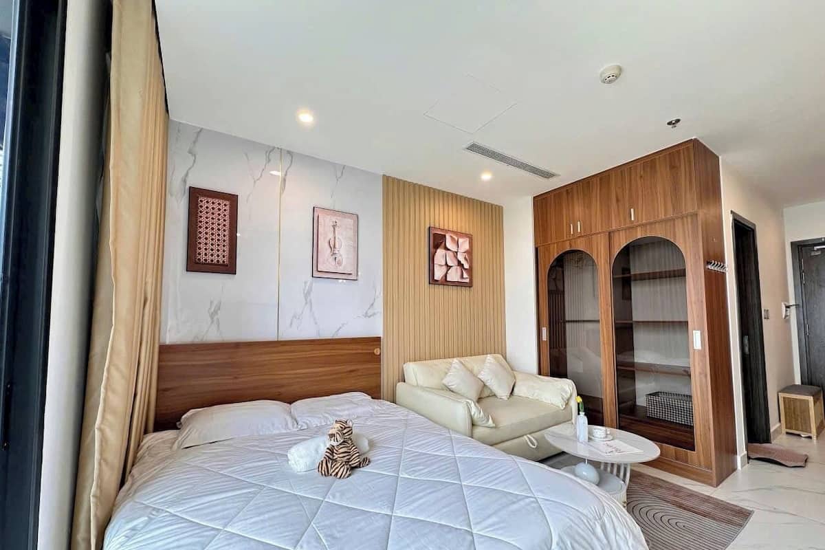 Une chambre d’hôtel avec un grand lit, un canapé, une petite table et une armoire.