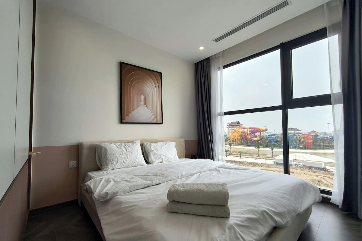 Une chambre d’hôtel dotée d’un grand lit, offrant une vue sur un parc aquatique et présentant un design moderne.