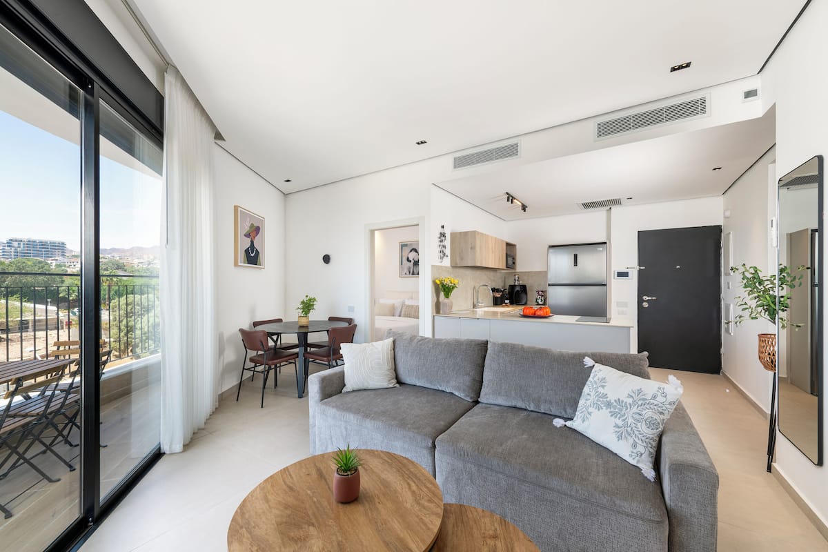 A modern apartment with a dining area, kitchen, and a balcony with a view.