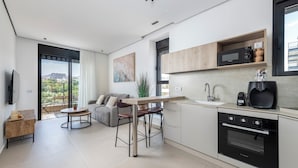 Una cucina moderna con forno integrato, microonde e macchina del caffè. C'è un'area pranzo con tavolo e sedie.